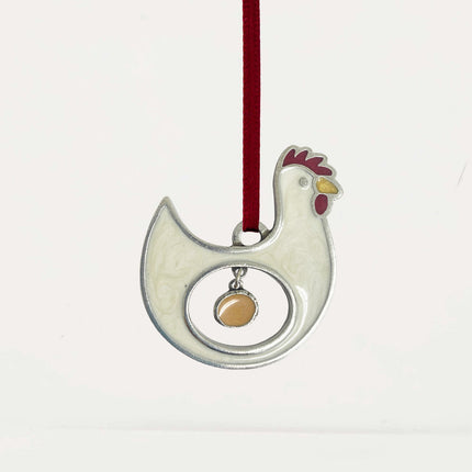pewter ornament of a chicken with a hollow center where an egg is hanging within the center