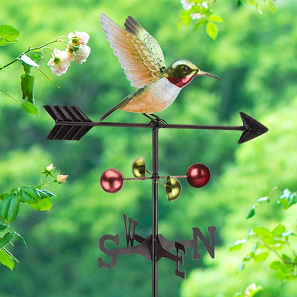 the hummingbird weathervane stake in a lush green garden