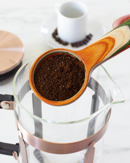 Coffee scoop in use, holding coffee grounds about to be placed in a coffee pot.