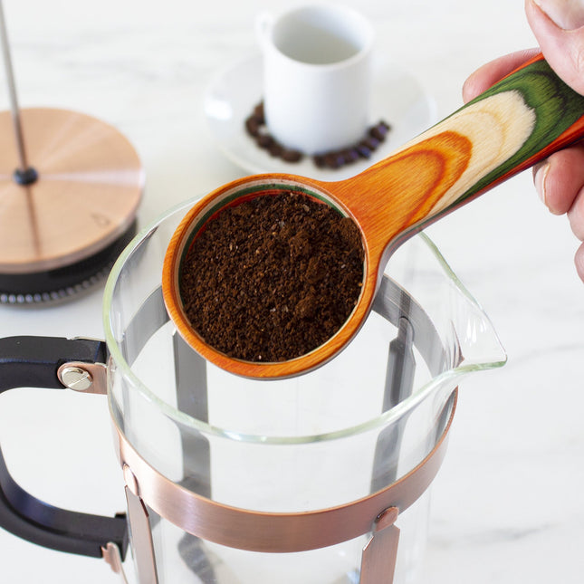 Coffee scoop in use, holding coffee grounds about to be placed in a coffee pot.