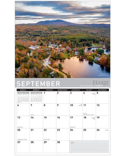 Calendar for September showing a scenic view of a town with trees in autumn colors.