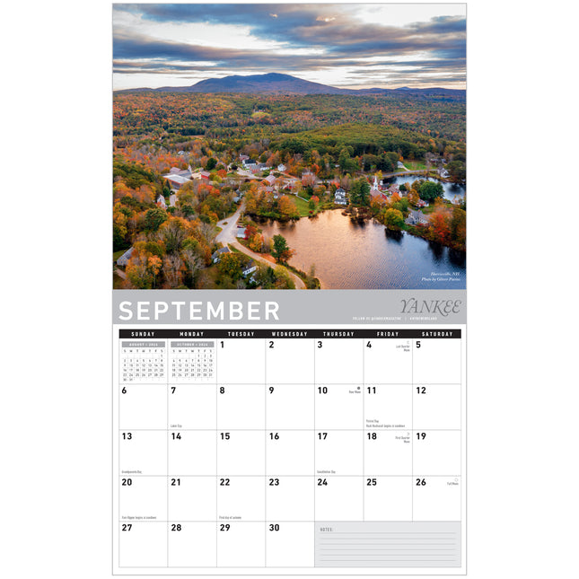 Calendar for September showing a scenic view of a town with trees in autumn colors.