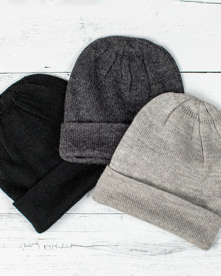 a trio of alpaca hats fanned on a white wood background - colors pictured are black, gray, and silver