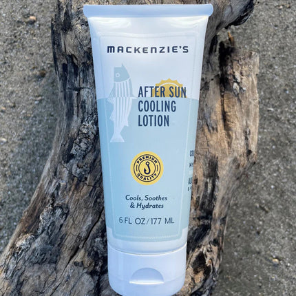 a bottle of after sun cooling lotion on a piece of driftwood on a sandy beach