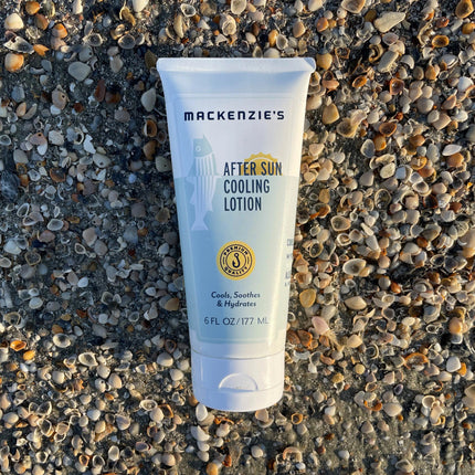 a bottle of after sun cooling lotion on a pebbled beach
