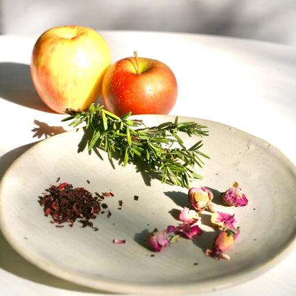 a plate with the fresh ingredients used in the shrub: apples, rosemary, hibiscus and rose petals
