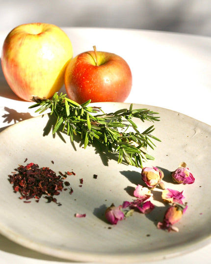 a plate with the fresh ingredients used in the shrub: apples, rosemary, hibiscus and rose petals