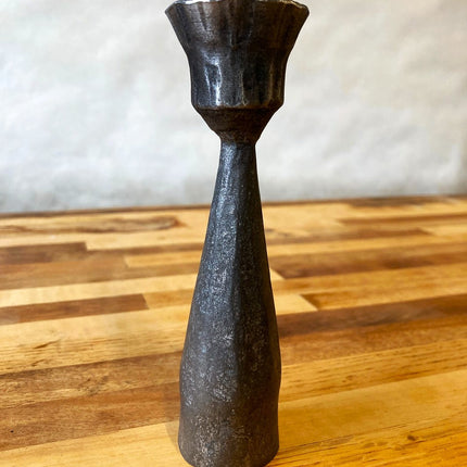 a closeup of the detail of a forged metal candlestick showing the subtle detail in the metalwork