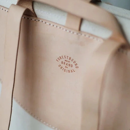 Close-up of a beige leather strap with 'Forestbound Brand Original' logo on a light background