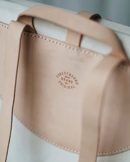Close-up of a beige leather strap with 'Forestbound Brand Original' logo on a light background