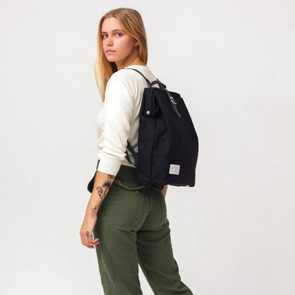 Person wearing a black backpack on a plain background