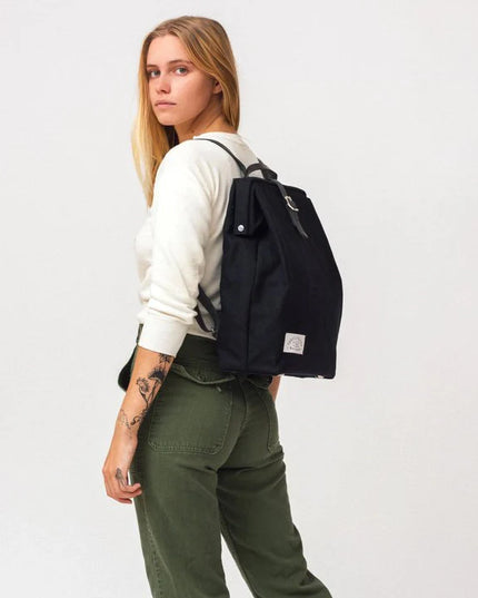 Person wearing a black backpack on a plain background