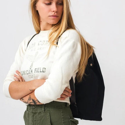 Woman wearing a white sweatshirt with text and green pants against a white background