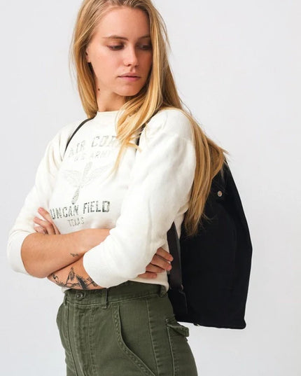 Woman wearing a white sweatshirt with text and green pants against a white background