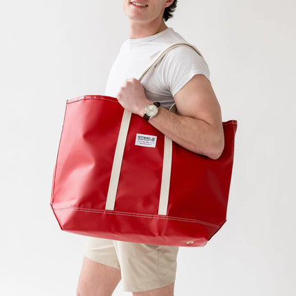 Person holding a red tote bag against a white background