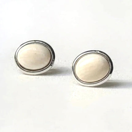 Pair of round earrings with pearly white center and silver rims on a white background