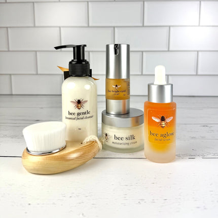Set of skincare products with bee-themed labels on a white surface and tiled wall background