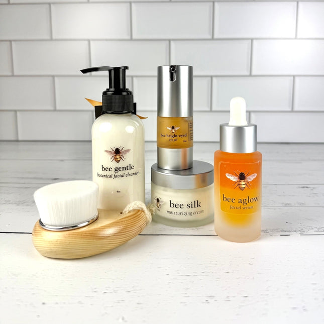 Set of skincare products with bee-themed labels on a white surface and tiled wall background