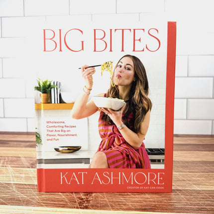 Book cover of 'Big Bites' by Kat Ashmore with a woman eating noodles.