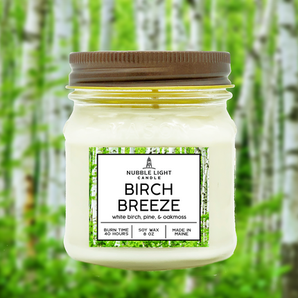 Jar candle labeled 'Birch Breeze' with a forest background