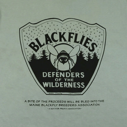 Closeup of black graphic of a blackfly on an emblem with the text "Blackflies Defenders of the Wilderness" on a sage green background
