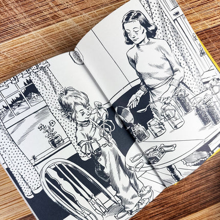 Illustrated book open to two pages with black and white drawings of a woman and child on a wooden surface.