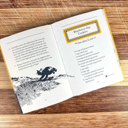 Open book with a recipe for blueberry oat cookies on a wooden surface