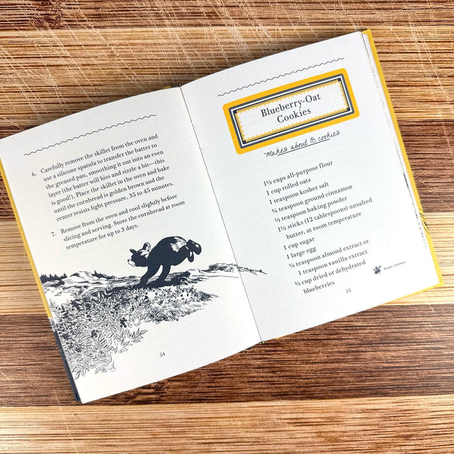Open book with a recipe for blueberry oat cookies on a wooden surface