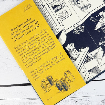 Book with yellow cover and black and white illustrations on a wooden surface