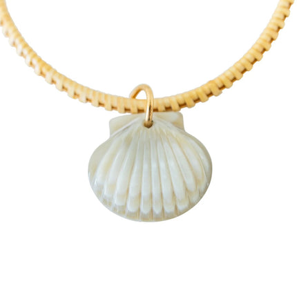 close up of the hand-carved seashell charm on a wooden bangle bracelet