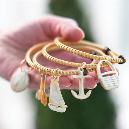 wooden bangle bracelets with various charms held by a hand against a blurred background