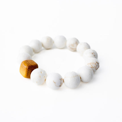 White beaded bracelet with a wooden accent on a white background