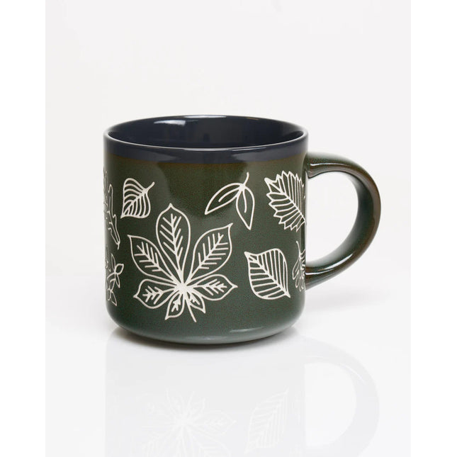 the other side of a forest green coffee mug with various leaf prints in white showing the outlines and details of various leaves in white with a vintage feel