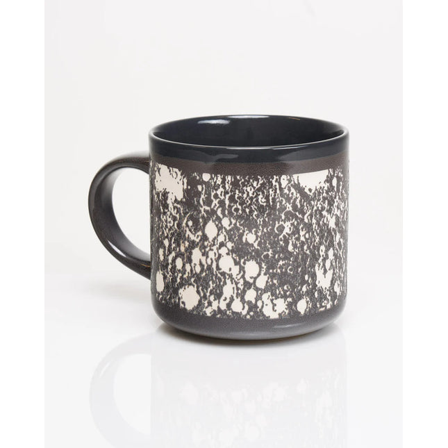 a gray ceramic mug with wrap around carved details of the surface of the moon in white