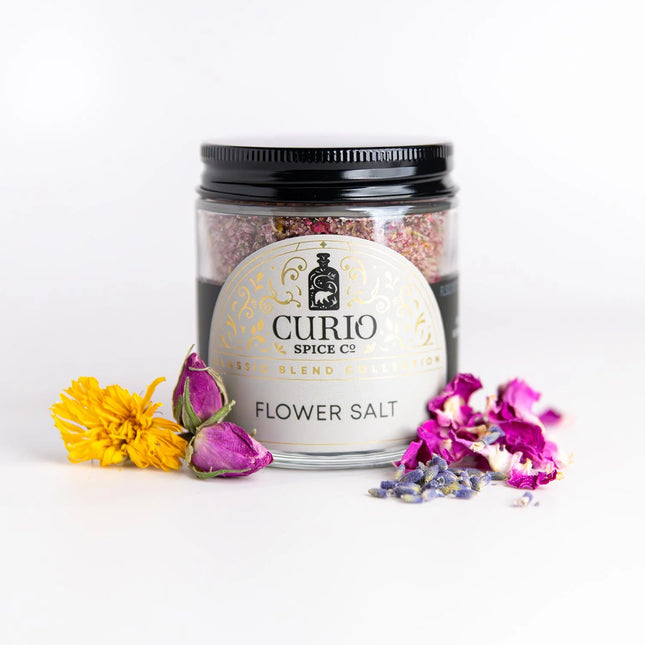 a jar of Curio Spice Flower Salt flanked by flowers
