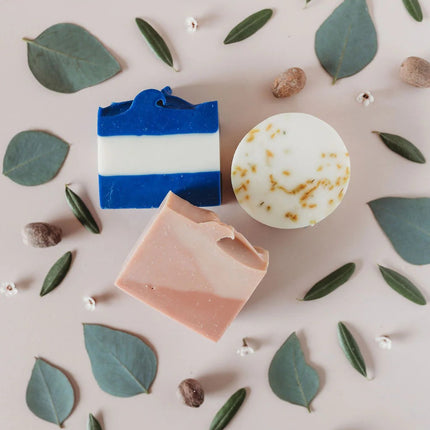 the three soaps in the Day at the Beach soap set surrounded by leaves and elements of the soap fragrances