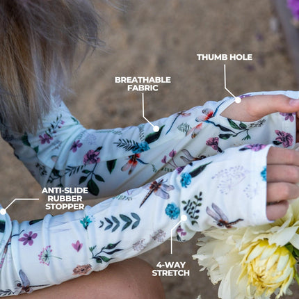 a close up of a model wearing the dragonfly meadow protection sleeves in the garden, showing off the convenient thumb hole. text on the image points out features of the sleeves including, "breathable fabric, thumb hole, anti-slide rubber stopper, and 4-way stretch