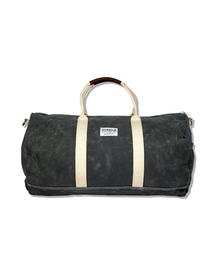 a gray waxed canvas duffle bag with white straps and leather handles