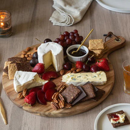 a snack spread of Effie's biscuits with cheese and fruit on a wood table surrounded by drinks and utensils