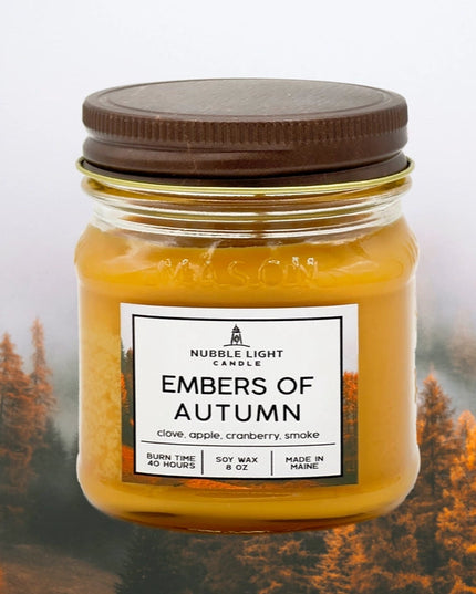 Jar candle labeled 'Embers of Autumn' with a forest background
