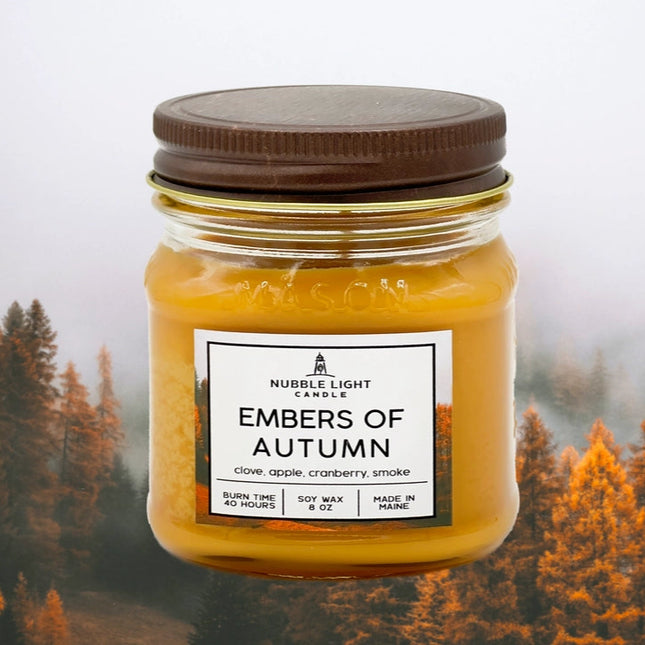 Jar candle labeled 'Embers of Autumn' with a forest background