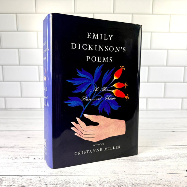 Book titled 'Emily Dickinson's Poems: As She Preserved them' with a hand holding flowers design on a black background.