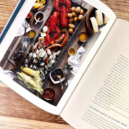 Open cookbook with a page showing a seafood platter on a wooden table.