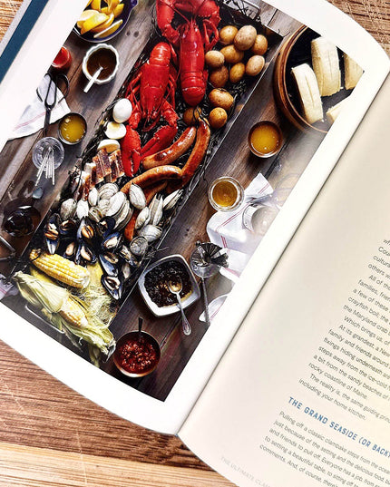 Open cookbook with a page showing a seafood platter on a wooden table.