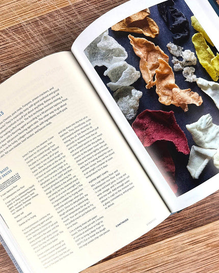 Open book with text and a colorful display of puffed snacks on a wooden surface