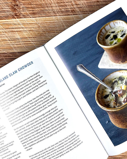 Open cookbook showing a page with New England Clam Chowder recipe and a photograph of the dish.