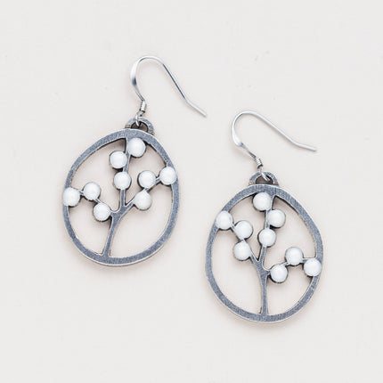 a pair of oval pewter earrings with branches inside adorned with white beads to represent blossoms