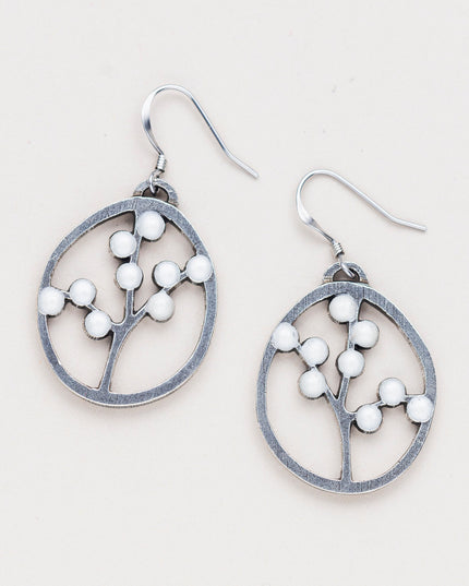 a pair of oval pewter earrings with branches inside adorned with white beads to represent blossoms