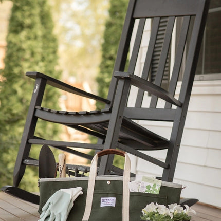 the garden tote loaded with tools resting on a porch alongside a rocking chair and pack of white flowers ready for planting