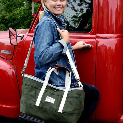 a model in a denim jacket with the garden tote slung over her shoulder with her hand on the door of a red truck